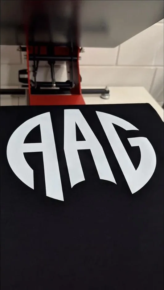 Groot wit logo van AAG op een zwart shirt