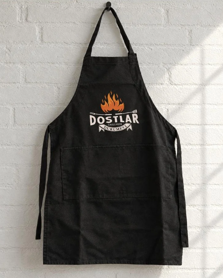 Zwart schort met logo van Dostlar Grillhuis aan een haak