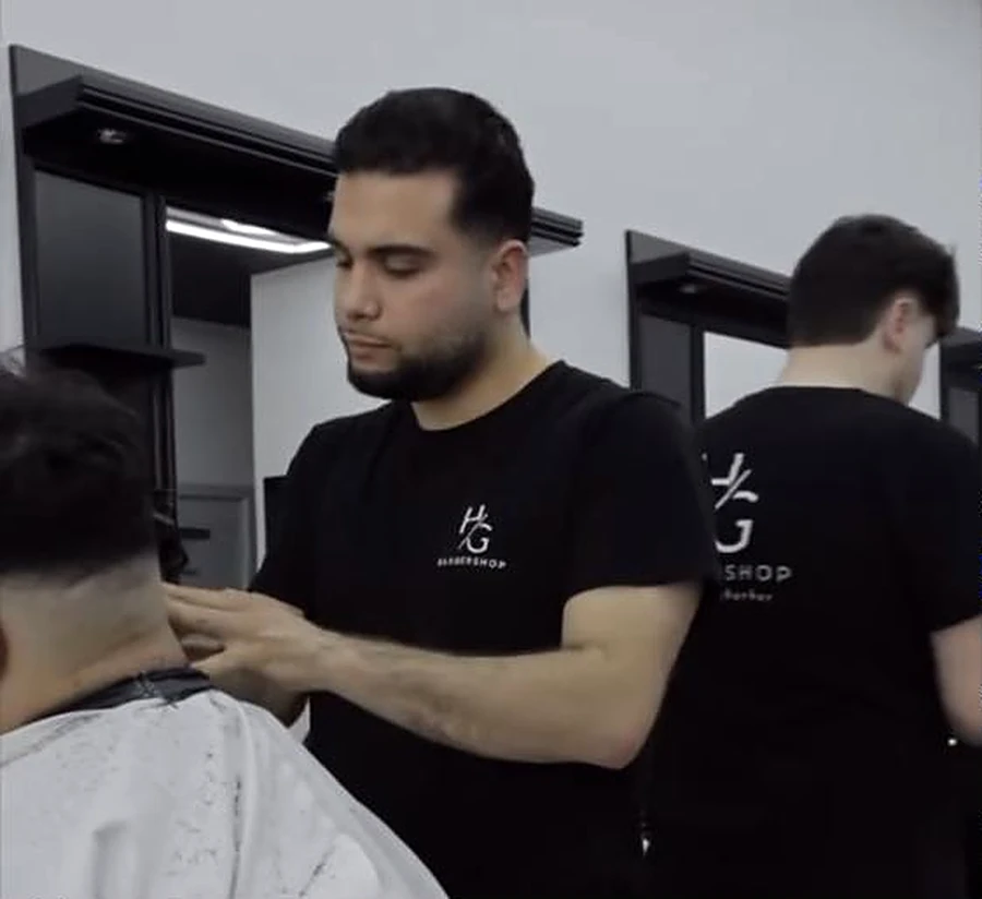 Barbers van Barbershop HG aan het werk in shirts met HG-logo