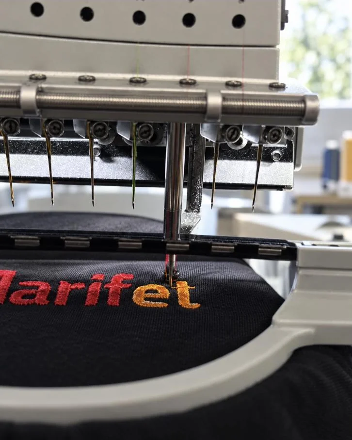 Borduurmachine borduurt het logo van Marifet op een zwart shirt